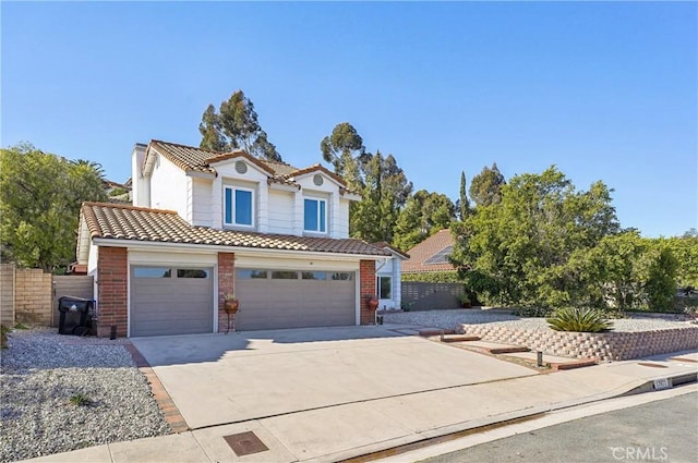 traditional-style house with a tile roof, fence, concrete driveway, and brick siding