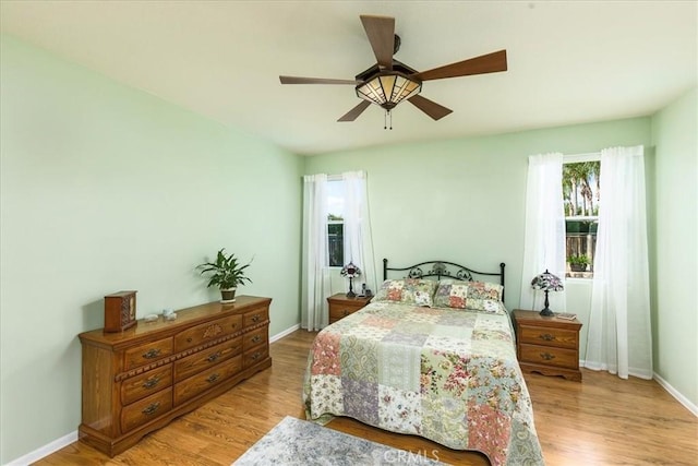 bedroom with ceiling fan, light wood-type flooring, and baseboards