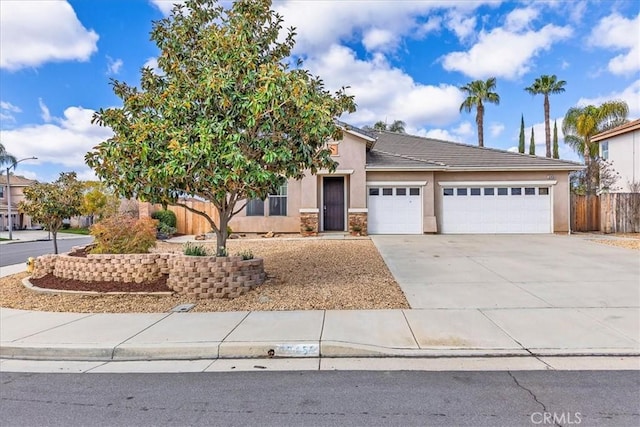 view of front of home featuring concrete driveway, fence, an attached garage, and stucco siding