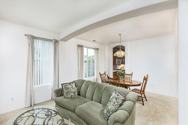 living room featuring carpet floors, arched walkways, and a notable chandelier