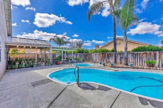 view of swimming pool featuring fence, a patio, and an in ground hot tub