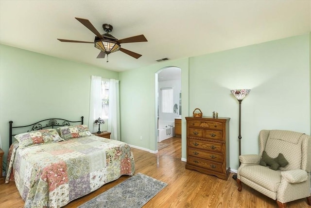 bedroom featuring visible vents, arched walkways, a ceiling fan, baseboards, and light wood-style flooring