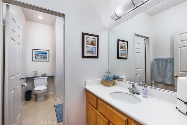 bathroom with toilet, vanity, baseboards, and tile patterned floors