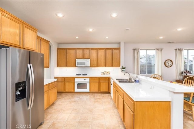 kitchen featuring recessed lighting, a peninsula, white appliances, a sink, and light countertops