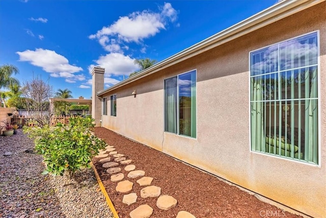 view of side of home featuring fence and stucco siding