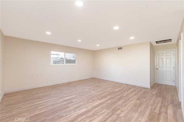 empty room featuring light wood finished floors, visible vents, baseboards, and recessed lighting