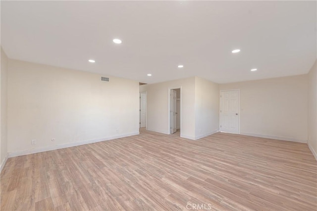 unfurnished room featuring baseboards, light wood-style flooring, visible vents, and recessed lighting