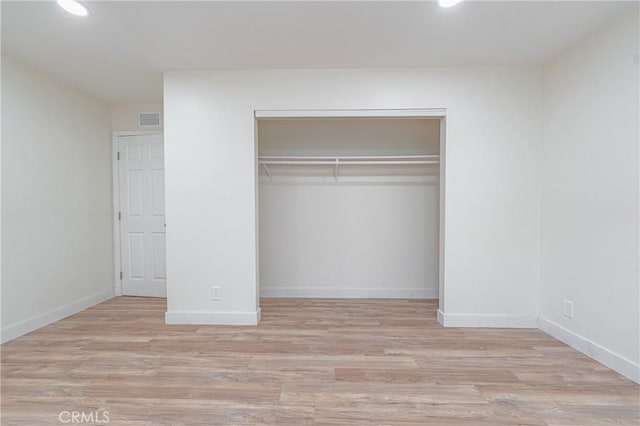 unfurnished bedroom featuring recessed lighting, wood finished floors, visible vents, baseboards, and a closet