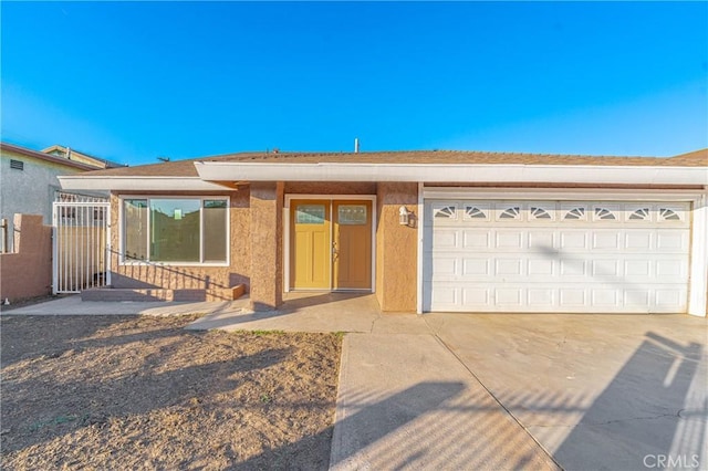 ranch-style house featuring driveway, an attached garage, and stucco siding