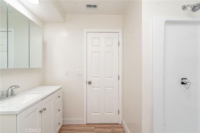 bathroom with vanity, wood finished floors, visible vents, and baseboards