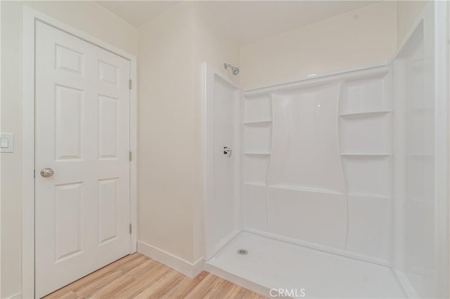 bathroom featuring a shower, wood finished floors, and baseboards