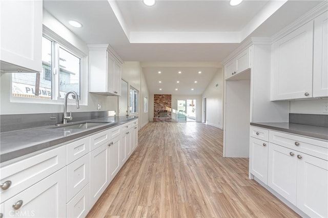 kitchen featuring dark countertops, recessed lighting, light wood-style flooring, white cabinetry, and a sink