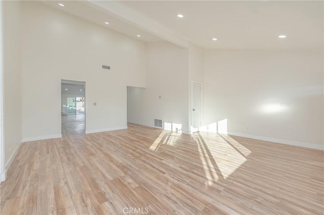 unfurnished living room with light wood-type flooring, visible vents, and baseboards