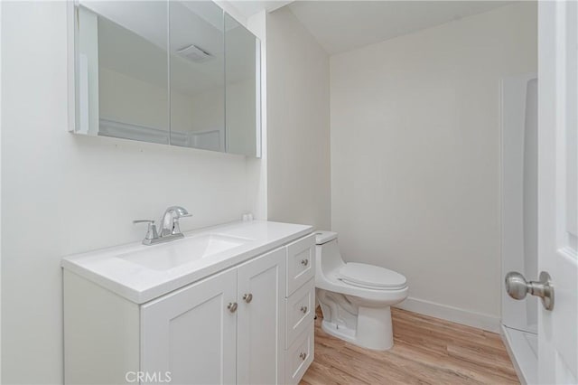 bathroom with baseboards, vanity, toilet, and wood finished floors