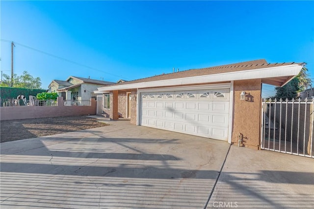 view of front of property featuring a garage, driveway, fence, and stucco siding