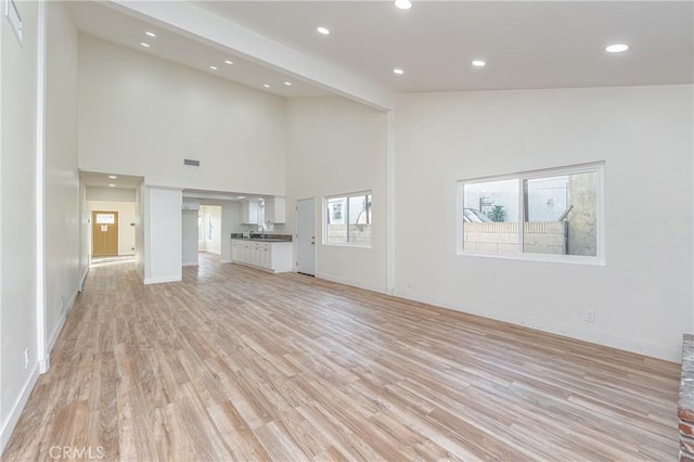 unfurnished living room with light wood-type flooring, visible vents, baseboards, and recessed lighting