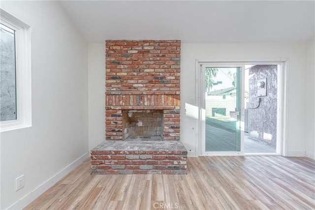 unfurnished living room featuring a fireplace, wood finished floors, and baseboards