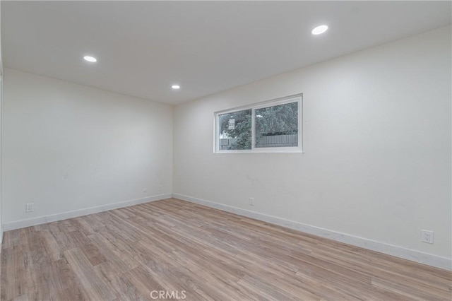 empty room featuring baseboards, light wood finished floors, and recessed lighting