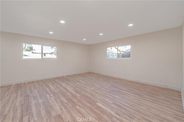 empty room featuring light wood-type flooring, a wealth of natural light, baseboards, and recessed lighting