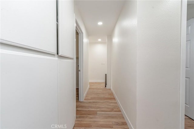 corridor featuring recessed lighting, baseboards, and light wood finished floors