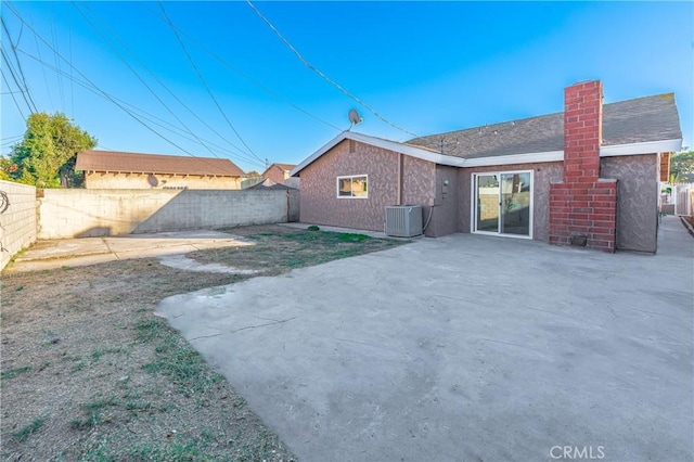 back of house with central AC, a fenced backyard, a patio, and a chimney