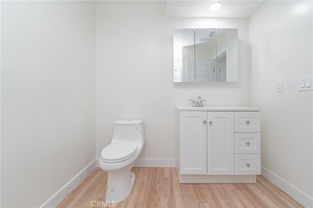 bathroom featuring baseboards, vanity, toilet, and wood finished floors