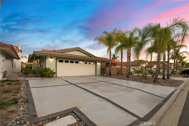 ranch-style home with an attached garage, a tile roof, concrete driveway, and stucco siding