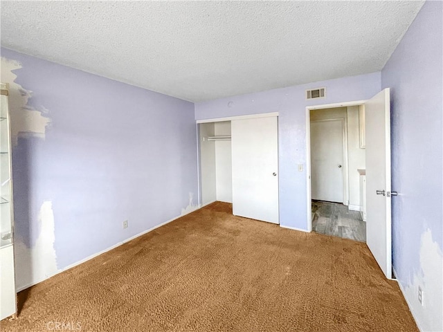 unfurnished bedroom with carpet, a closet, visible vents, and a textured ceiling