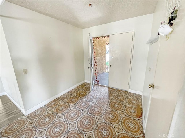 tiled foyer entrance featuring a textured ceiling and baseboards