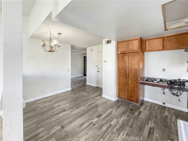 kitchen with baseboards, visible vents, brown cabinetry, wood finished floors, and a textured ceiling