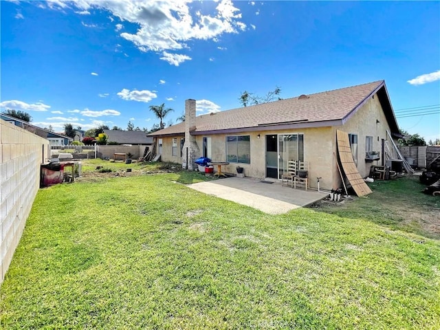 back of house with a lawn, a patio, a fenced backyard, a chimney, and stucco siding