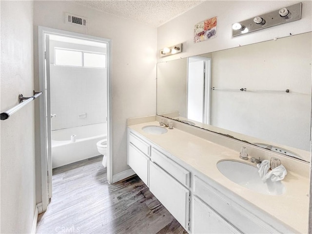 full bath featuring a textured ceiling, toilet, a sink, and visible vents