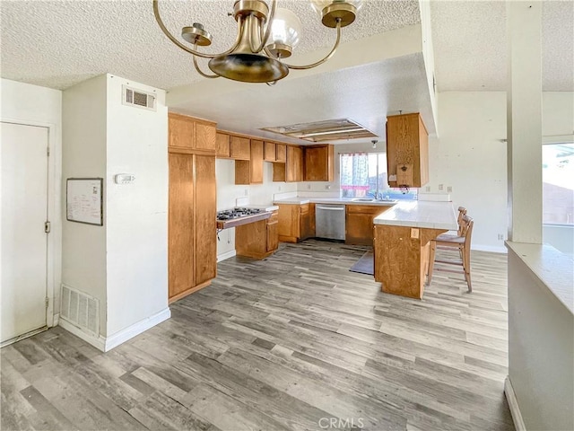 kitchen featuring a peninsula, visible vents, appliances with stainless steel finishes, and brown cabinets