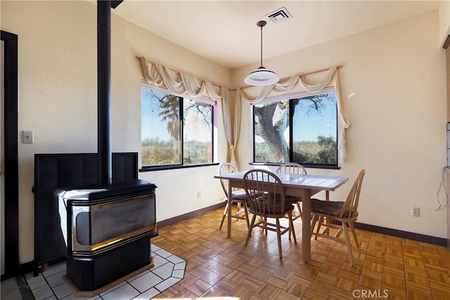 dining area featuring visible vents, a wood stove, and baseboards