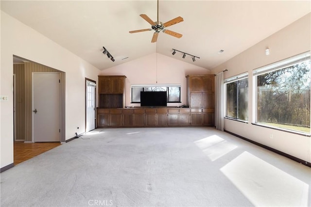 unfurnished living room featuring ceiling fan, light colored carpet, vaulted ceiling, track lighting, and baseboards
