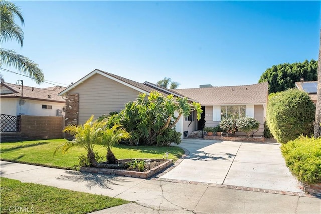 single story home with brick siding, fence, a garage, driveway, and a front lawn