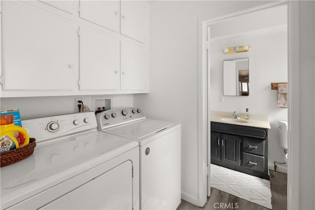 washroom featuring cabinet space, wood finished floors, a sink, and independent washer and dryer