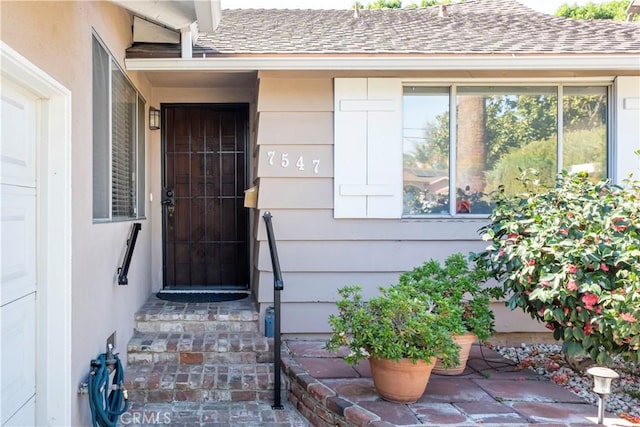 doorway to property with roof with shingles