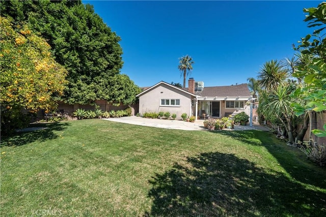 rear view of house featuring a lawn, a patio area, fence, and stucco siding