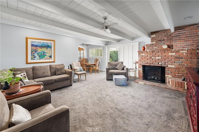 carpeted living area featuring a brick fireplace, ceiling fan, and beam ceiling