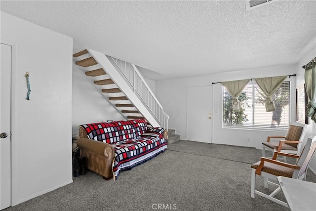 sitting room featuring stairs, carpet floors, a textured ceiling, and visible vents