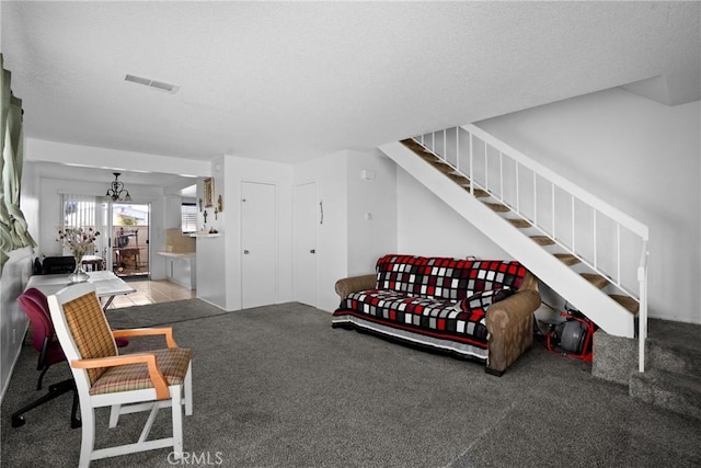 carpeted living room with stairs, a textured ceiling, and visible vents