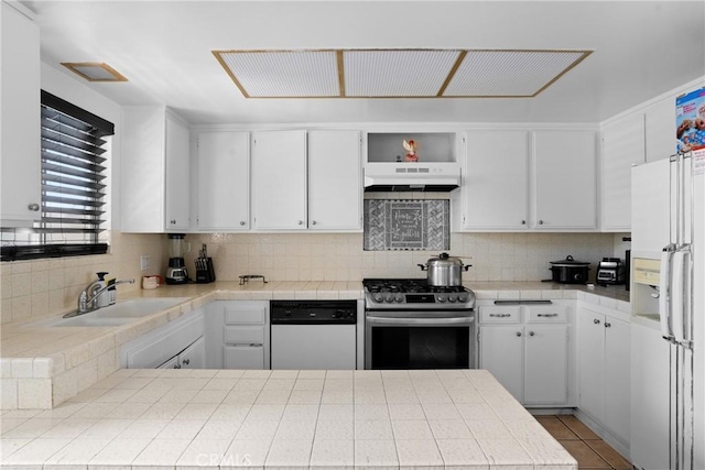 kitchen with tile countertops, white appliances, under cabinet range hood, and decorative backsplash