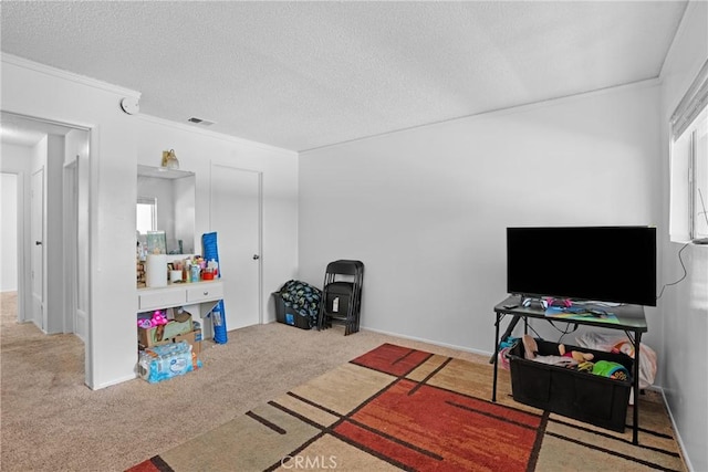 recreation room with carpet, crown molding, visible vents, and a textured ceiling