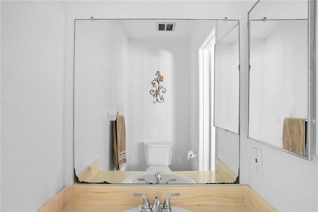 bathroom featuring toilet, visible vents, and a sink