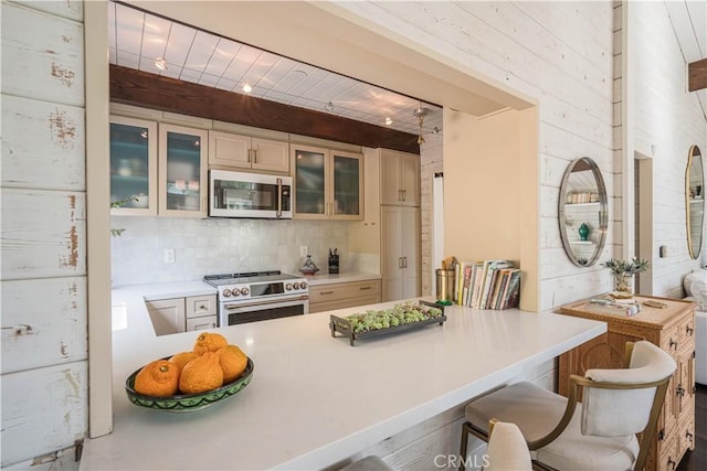 kitchen with stainless steel appliances, a peninsula, glass insert cabinets, and decorative backsplash