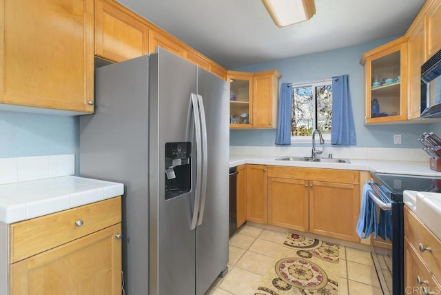 kitchen featuring black electric range, stainless steel refrigerator with ice dispenser, a sink, and tile counters