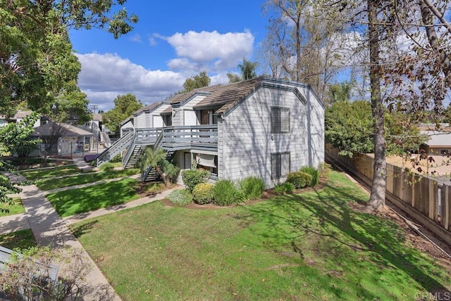 exterior space featuring stairs, fence, and a yard