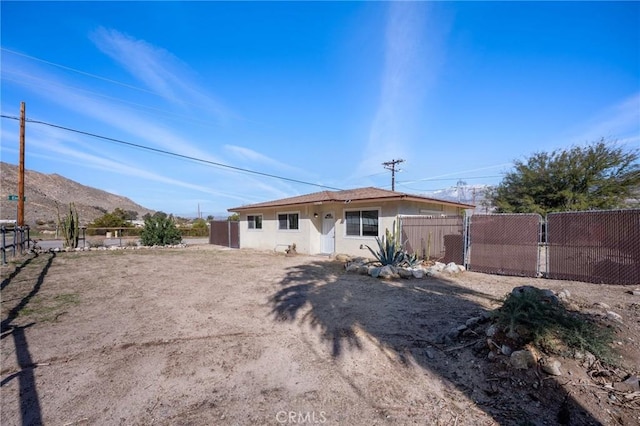 view of front of house with fence, a mountain view, and stucco siding