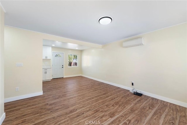 unfurnished room with a wall mounted air conditioner, wood finished floors, and baseboards